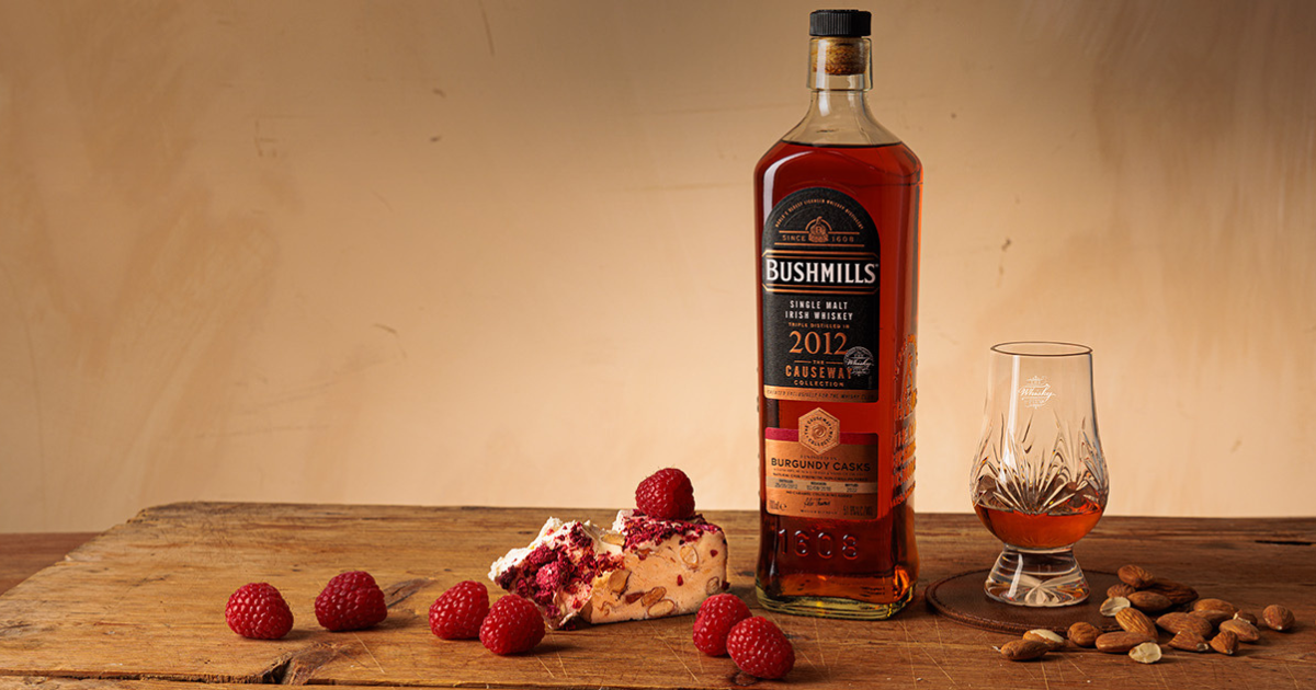 A bottle of Bushmills 2012 Burgundy Cask surrounded by fruit and nuts 